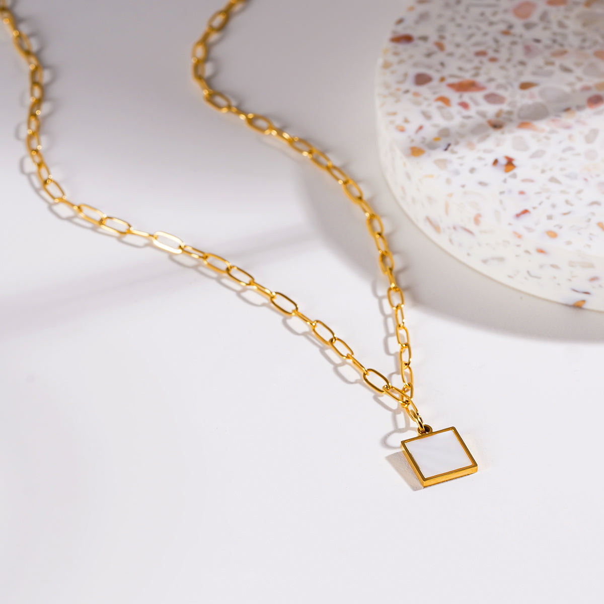 Style ANNABELLA : Pendentif carré minimaliste en métal et coquillage sur une chaîne trombone.